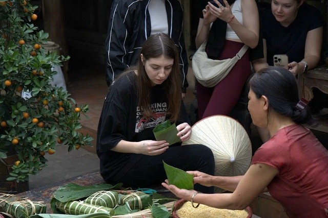 Du khách trải nghiệm gói bánh chưng trong Tết Làng Việt. Ảnh: VGP