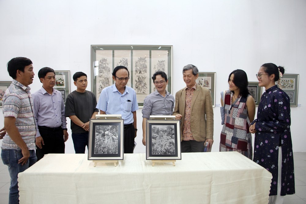 Họa sĩ Nguyễn Ngọc Vinh (đứng thứ 4, từ phải qua) giới thiệu các tác phẩm tranh dân gian Đông Hồ trên chất liệu inox. Ảnh: BTC