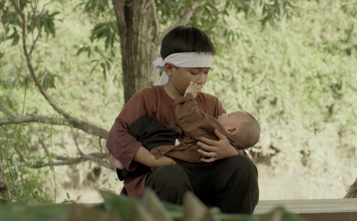 Cậu bé Côn bế em đi xin sữa, em khóc ngặt trên tay. Ảnh: BTC