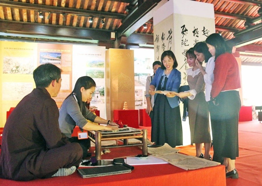 Du khách trải nghiệm in mộc bản chùa Vĩnh Nghiêm tại triển lãm thành tựu “Di sản ngàn năm Yên Tử - Vĩnh Nghiêm - Côn Sơn, Kiếp Bạc”. Ảnh: N.H