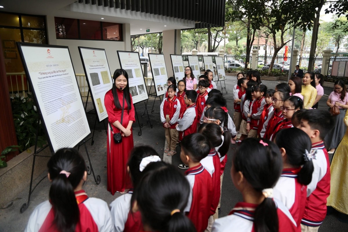 Các em học sinh nghe giới thiệu Tết hoàng cung qua Mộc bản triều Nguyễn. Ảnh: BTC